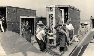 Varios hombres desembalan un Spitfire de su cajón de transporte